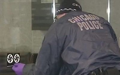A police officer removes swastika stickers from the front of the Loop Synagogue in Chicago on February 4, 2017, following what authorities said was a hate crime (screen capture: NBC Chicago)
