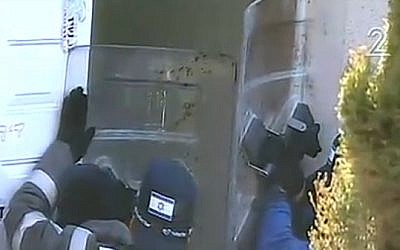 Police hold up plastic shields, as protesters throw bottles and other objects at them from inside the Amona outpost's synagogue on February 2, 2017. (Screen capture: Channel 2)