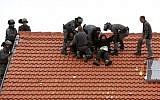Israeli police remove protesters from the roof of a home slated to be destroyed in the West Bank settlement of Ofra on March 1, 2017. (AFP Photo/Menahem Kahana)