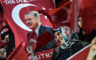 A woman stands near a flag bearing a Turkish President Recep Tayyip Erdogan's picture on March 5, 2017 in Istanbul during a pro-government women's meeting. (AFP Photo/Ozan Kose)
