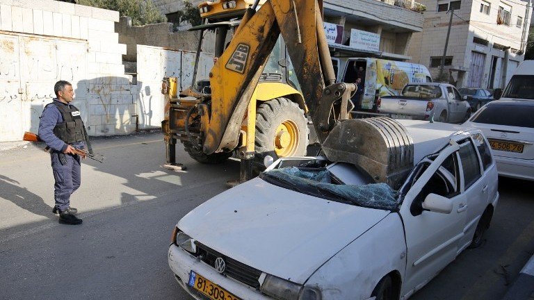 A bulldozer smashes its shovel into a car with an Israeli license plate in the West Bank village of al-Ram on March 6, 2017. (AFP Photo/Abbas Momani) A bulldozer smashes its shovel into a car with an Israeli license plate in the West Bank village of al-Ram on March 6, 2017. (AFP Photo/Abbas Momani)