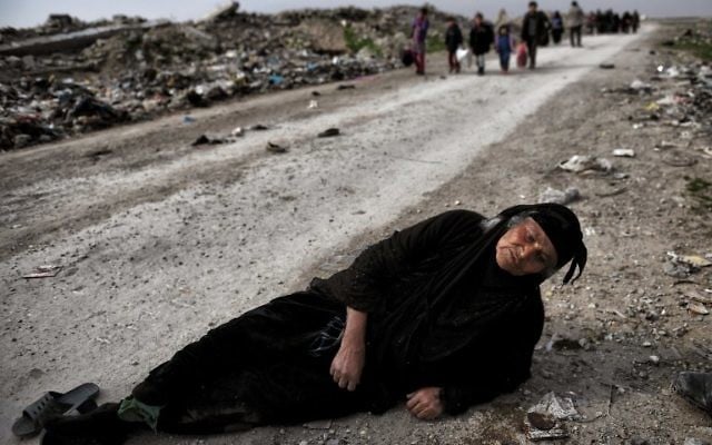 An Iraqi woman lies on the ground as civilians flee Mosul while Iraqi forces advance inside the city during fighting against Islamic State group's fighters on March 8, 2017. AFP PHOTO / ARIS MESSINIS