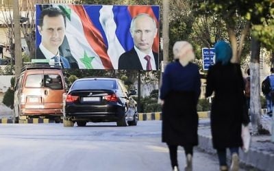 Syrians walking past a giant poster of Syrian President Bashar Assad (L) and his Russian counterpart Vladimir Putin (R) in the northern Syrian city of Aleppo, March 9, 2017. (AFP Photo/Joseph Eid/ File)