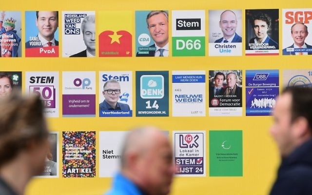 People walk past an electoral poster depicting all candidates on March 14, 2017 in The Hague, on the eve of the Dutch general election. ( AFP PHOTO / Emmanuel DUNAND)