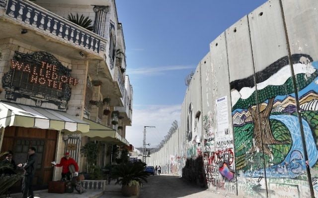 The Israeli controversial separation wall is seen in front of artist Banksy's newly opened Walled Off hotel in the Israeli occupied West Bank town of Bethlehem, on March 15, 2017. (Thomas Coex/AFP) The Israeli controversial separation wall is seen in front of artist Banksy's newly opened Walled Off hotel in the Israeli occupied West Bank town of Bethlehem, on March 15, 2017. (Thomas Coex/AFP)