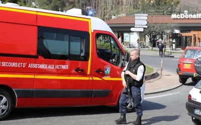 A policeman wearing a bulletproof vest stands near a firefighters vehicle on a road near the Tocqueville high school in the southern French town of Grasse, on March 16, 2017 following a shooting that left two people injured. (Valery Hache/AFP)