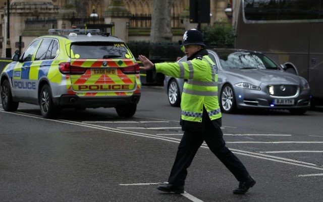 A police officer stops traffic as the Jaguar car of British Prime Minister Theresa May (R) is driven away from the Houses of Parliament in central London on March 22, 2017 during an emergency incident. (AFP PHOTO / Daniel LEAL-OLIVAS)