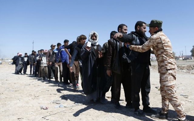 Displaced Iraqis, who fled their homes due to the ongoing fighting between government forces and Islamic State (IS) group fighters, are checked as they arrive on March 25, 2017, to be taken to camps as an ongoing operation against the jihadists continues in the city of Mosul. ( AFP PHOTO / AHMAD GHARABLI)