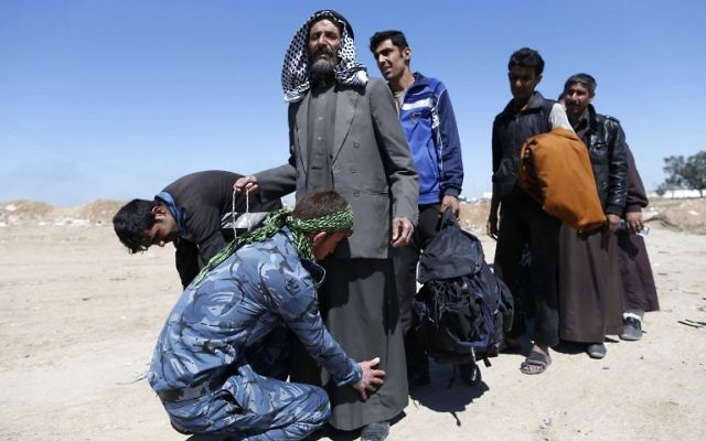 Displaced Iraqis, who fled their homes due to the ongoing fighting between government forces and Islamic State (IS) group fighters, are checked as they arrive on March 25, 2017, to be taken to camps as an ongoing operation against the jihadists continues in the city of Mosul. ( AFP PHOTO / AHMAD GHARABLI)