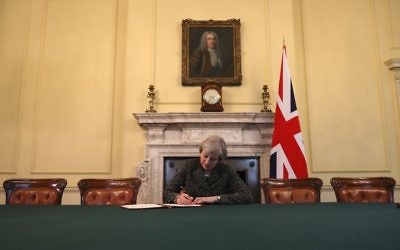Britain's Prime Minister Theresa May, sits below a painting of Britain's first Prime Minister Robert Walpole, as she signs the official letter to European Council President Donald Tusk, invoking Article 50 and signaling the United Kingdom's intention to leave the EU, in the cabinet office inside 10 Downing Street on March 28, 2017. (AFP Photo/Pool/Christopher Furlong)