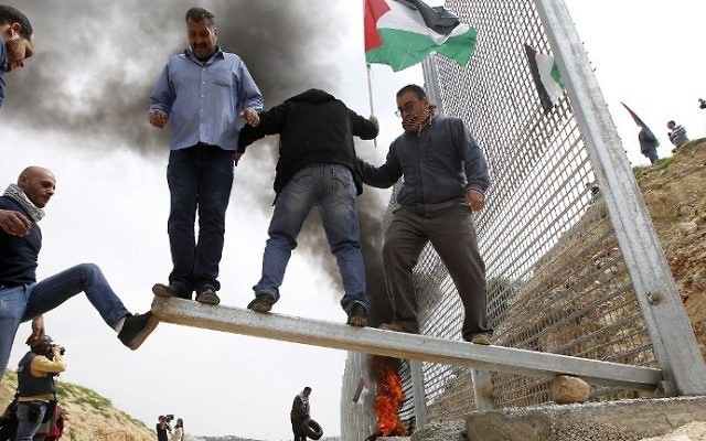Illustrative: Palestinian demonstrators attempt to damage an iron fence, setup by Israeli security forces, between the Palestinian village of Beit Jala and the Jerusalem area, on March 30, 2017 during Land Day protest in the Israeli occupied West Bank. (AFP PHOTO / Musa AL SHAER) Illustrative: Palestinian demonstrators attempt to damage an iron fence, setup by Israeli security forces, between the Palestinian village of Beit Jala and the Jerusalem area, on March 30, 2017 during Land Day protest in the Israeli occupied West Bank. (AFP PHOTO / Musa AL SHAER)