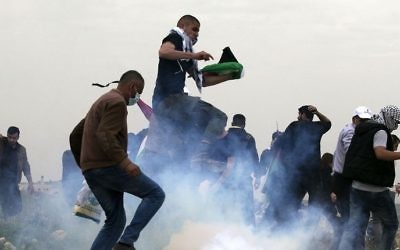 Palestinian demonstrators run as Israeli security forces fire tear gas toward them following a protest to mark Land Day in the village of Madama, south of Nablus, in the West Bank, March 30, 2017. (AFP/JAAFAR ASHTIYEH)