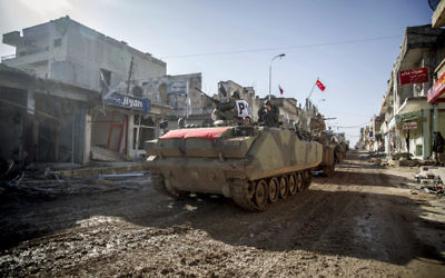 In this February 22, 2015, file photo, the Turkish army's armored vehicles and tanks drive in Syrian town of Ayn al-Arab, also known as Kobani, as they return from the Ottoman tomb in Syria. (AP Photo/Mursel Coban)