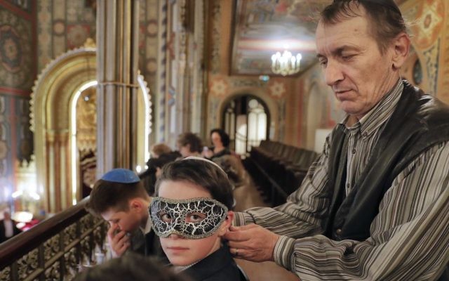 In this March 11, 2017 picture, a man puts a mask on a boy before Purim celebrations at the Coral Temple synagogue in Bucharest, Romania. Children put on fancy costume dress joining dozens of believers from Romania's Jewish community who attended a Purim service to celebrate the Jews' salvation from genocide in ancient Persia, as recounted in the Book of Esther. (AP Photo/Vadim Ghirda)