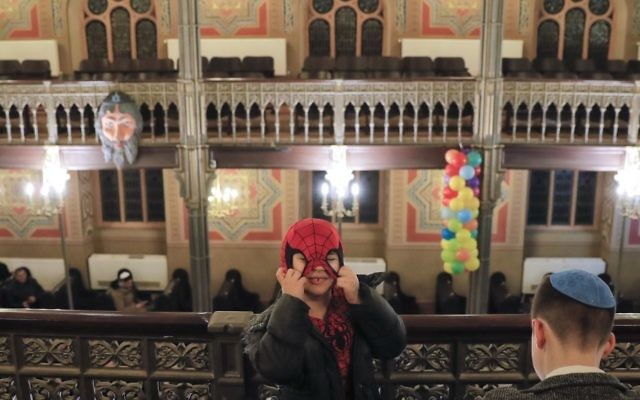 In this March 11, 2017 picture, a child puts on the mask of his Spiderman costume before Purim celebrations at the Coral Temple synagogue in Bucharest, Romania. (AP Photo/Vadim Ghirda)