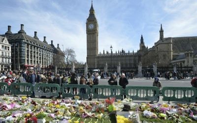 People look at tributes in Parliament Square, London, Saturday, March 25, 2017, laid out for the victims of the Westminster attack on March 22, 2017. (John Stillwell/PA via AP)