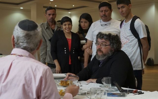 In this March 19, 2017 photo, a rabbi fills out paperwork in Bogota, Colombia, making the conversion of nine Venezuelans to Judaism official before their departure to Israel. (AP Photo/Christine Armario)