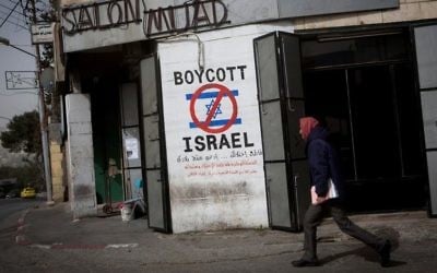 Illustrative: A Palestinian man walks past graffiti calling for a boycott of Israel on a street in the West Bank city of Bethlehem on February 11, 2015. (Miriam Alster/Flash 90)