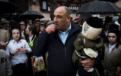 A police officer holds a large doll dressed as a religious soldier that was hang in the ultra-Orthodox Jerusalem neighborhood of Mea Shearim on March 13, 2017. (Nati Shohat/Flash90)