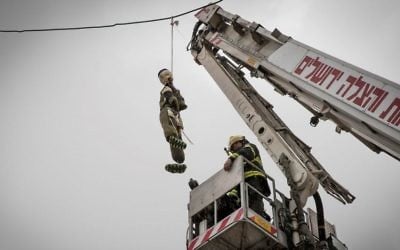 A firefighter takes down a large doll dressed as an ultra-Orthodox Jewish soldier hung in the ultra-Orthodox Jerusalem neighborhood of Mea Shearim, on March 13, 2017. (Nati Shohat/Flash90)