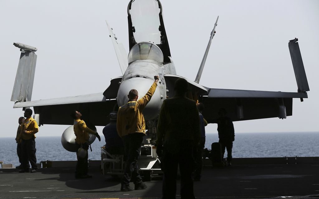 In this Wednesday, March 22, 2017 photograph, crew bring an F-18 below deck on the USS George H.W. Bush as it travels through the Persian Gulf. The carrier soon will begin launching airstrikes targeting the Islamic State group in Iraq and Syria. (AP Photo/Jon Gambrell)