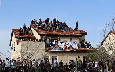 Protesters sit on a rooftop of a home during an operation to evacuate nine homes in the Jewish settlement of Ofra, in the West Bank, February 28, 2017. (Raoul Wootliff/Times of Israel)