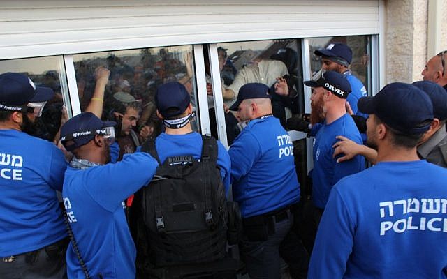 Police forcibly opening the back doors of a house in the West Bank Ofra settlement, February 28, 2017. (Raoul Wootliff/Times of Israel)