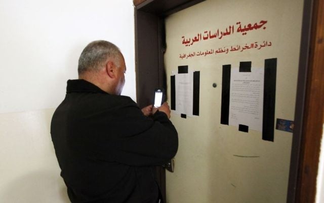 A man takes a photo of the sealed offices of Khalil Tufagji, a prominent Palestinian cartographer, in East Jerusalem, Tuesday, March 14, 2017. (AP Photo/Mahmoud Illean)