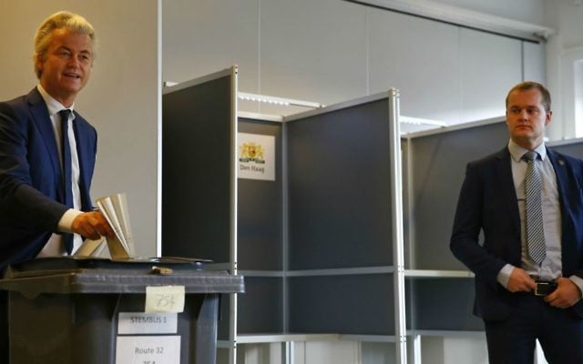 A security guard looks on as Geert Wilders, left, casts his ballot for the Dutch general election in The Hague, Netherlands, Wednesday, March 15, 2017. (AP Photo/Peter Dejong)