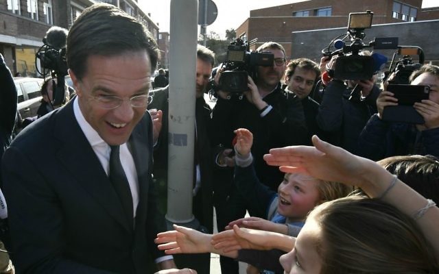 Dutch Prime Minister Mark Rutte shakes hands with children after casting his vote for the Dutch general election in The Hague, Netherlands, Wednesday, March 15, 2017. (AP Photo/Patrick Post)