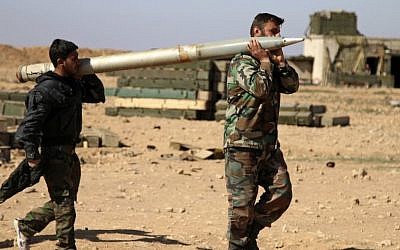In this Feb. 17, 2016 file photo, soldiers from the Syrian army carry a rocket as they prepare to fire at Islamic State group positions in the province of Raqqa, Syria. (Alexander Kots/Komsomolskaya Pravda via AP)
