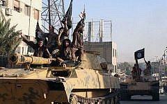 In this undated image posted by the Raqqa Media Center, in Islamic State group-held territory, on Monday, June 30, 2014, which has been verified and is consistent with other AP reporting, fighters from the Islamic State group ride tanks during a parade in Raqqa, Syria.  (Raqqa Media Center via AP)