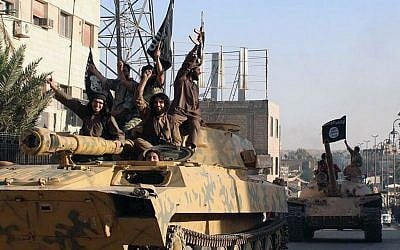 In this undated image posted by the Raqqa Media Center, in Islamic State group-held territory, on Monday, June 30, 2014, which has been verified and is consistent with other AP reporting, fighters from the Islamic State group ride tanks during a parade in Raqqa, Syria. (Raqqa Media Center via AP)