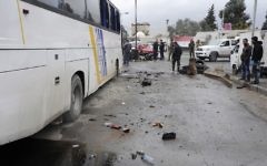 People inspect damage in a parking lot at the site of an attack by twin explosions in Damascus, Syria, Saturday, March 11, 2017 (SANA via AP)