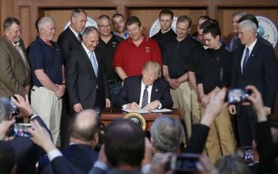President Donald Trump, accompanied by Environmental Protection Agency (EPA) Administrator Scott Pruitt, third from left, and Vice President Mike Pence, right, signs an Energy Independence Executive Order, March 28, 2017, at EPA headquarters in Washington. (AP Photo/Pablo Martinez Monsivais)