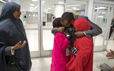 Ismail Issack, father of Miski Shalle, 11, and Muzamil Shalle, 14, embraces his children as their mother Halima Mohamed, far left, looks on as they reunite for the first time in seven years at John F. Kennedy International Airport in New York Wednesday, March 8, 2017. (AP Photo/Craig Ruttle)
