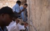 Workers clean notes with prayers written on them from the Western Wall ahead of Passover, in a biannual cleaning, March 29, 2017. (Luke Tress/Times of Israel)