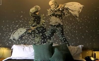 Banksy's depiction of a pillow-fight between an Israeli soldier and a Palestinian that is painted on the wall of one of the room's in the artist Banksy's new Bethlehem hotel in the West Bank (Screen capture/YouTube)