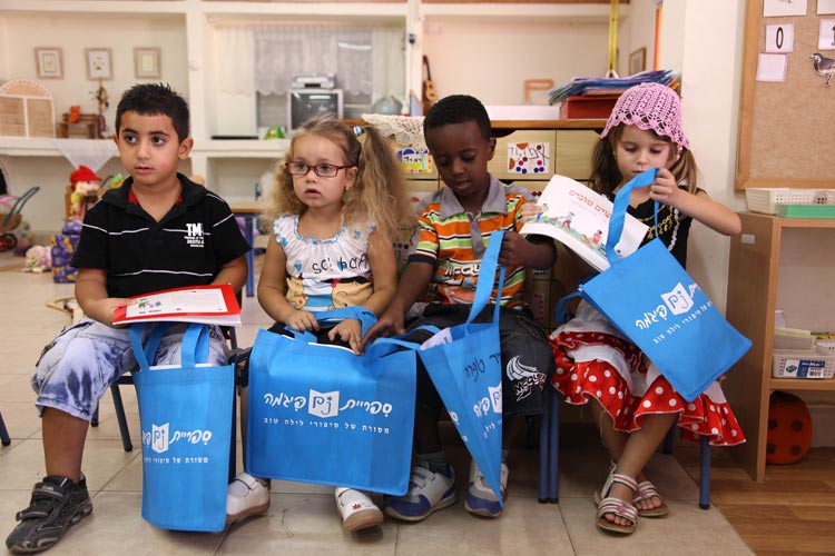 Preschool kids getting their Sifriyat Pijama books in the bags given out by the PJ Library program (Courtesy PJ Library)