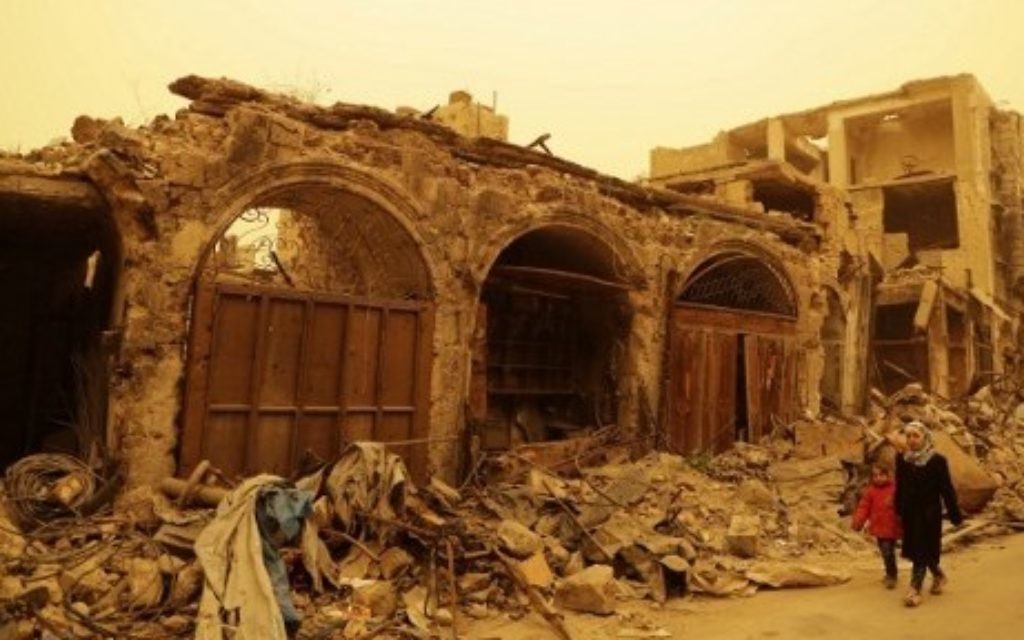 Syrian girls walk past destroyed buildings during a sandstorm in the once rebel-held Bab al-Nasr neighborhood in the old part of Aleppo on March 10, 2017. (AFP/Joseph Eid)
