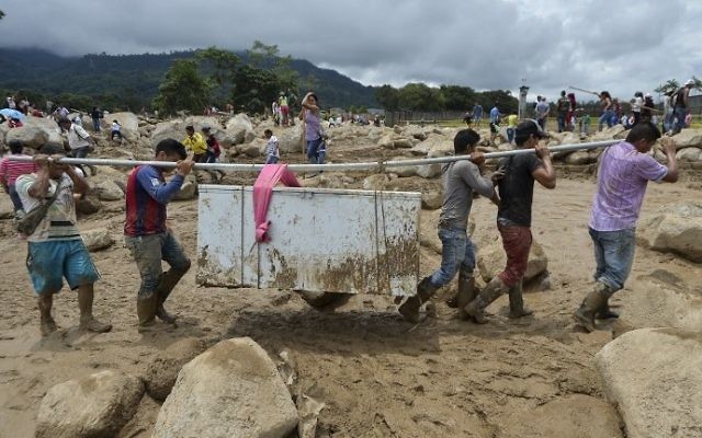 People carry their belongings amidst the rubble left by mudslides following heavy rains in Mocoa, Putumayo department, southern Colombia on April 2, 2017. (AFP PHOTO / LUIS ROBAYO)