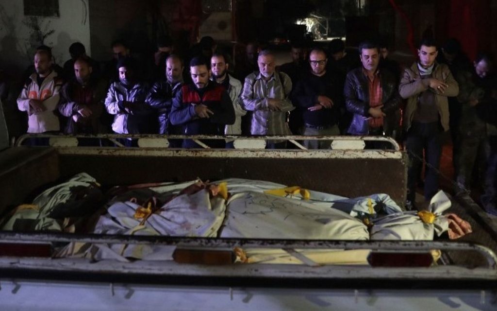 Syrian mourners pray next to bodies lying in the back of a pick up truck outside  a makeshift morgue following reported air strikes by government forces in the rebel-held town of Douma, on the eastern outskirts of Damascus, on April 3, 2017. (AFP PHOTO / Abd Doumany)