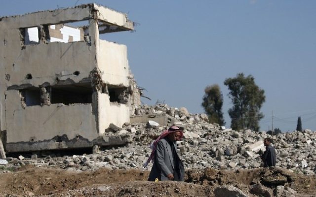 Iraqis walk past a damaged building as they leave Mosul's Old City on April 4, 2017, during an offensive by government forces to retake the city from Islamic State (IS) group fighters. (AFP PHOTO / AHMAD GHARABLI)