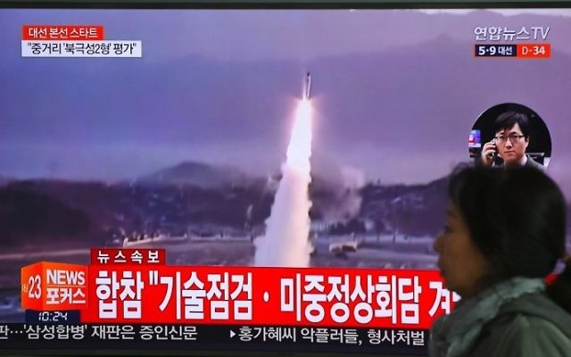 A woman walks past a television screen showing file footage of a North Korean missile launch, at a railway station in Seoul on April 5, 2017. (AFP Photo/Jung Yeon-Je)