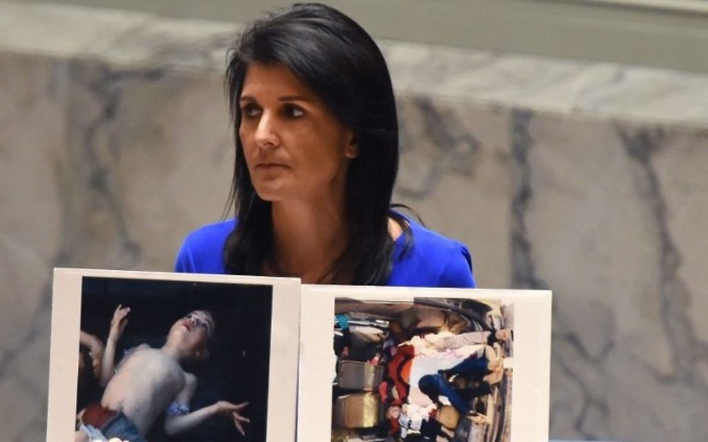 US Ambassador to the UN Nikki Haley holds photos of victims as she speaks at the UN Security Council in an emergency session on April 5, 2017 about the suspected deadly chemical attack that killed civilians, including children, in Syria. (AFP/Timothy A. Clary)
