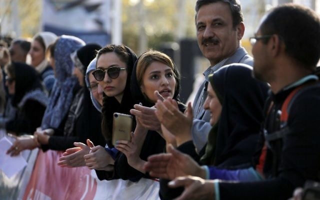 Foreigners and locals watch the first international Tehran marathon at Azadi Square in the Iranian capital on April 7, 2017.(AFP PHOTO / ATTA KENARE)