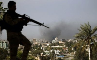 A member of the Iraqi forces stands guard over a building in the eastern part of the northern Iraqi city of Mosul on April 7, 2017 as smoke rises from the old city during the offensive by Iraqi forces to retake it from Islamic State fighters.  (AFP PHOTO / AHMAD GHARABLI)