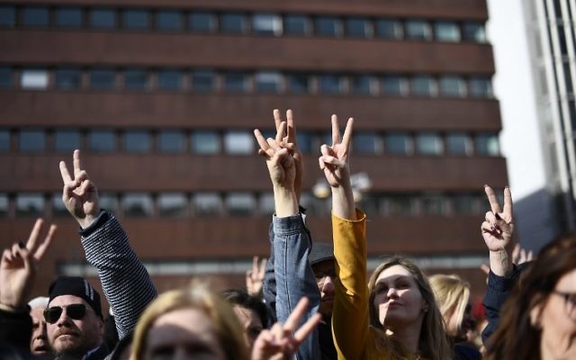People flash the victory sign as they attend a memorial ceremony at Sergels Torg plaza in Stockholm, Sweden on April 9, 2017 close to the point where a truck drove into a department store two days before. (AFP PHOTO / Jonathan NACKSTRAND)