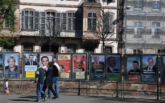 People walk past campaign posters of the 11 candidates for the French presidential election on April 10, 2017 in Strasbourg, eastern France. (AFP PHOTO / FREDERICK FLORIN)