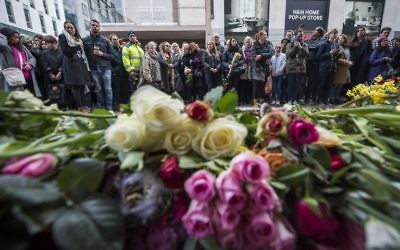 People react during a minute of silence to commemorate the victims of Friday's terror attack at a makeshift memorial near the site where a truck drove into Ahlens department store in Stockholm, Sweden, on April 10, 2017. ( AFP PHOTO / Jonathan NACKSTRAND)